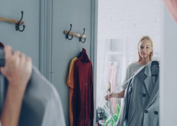 A woman reviewing her London wardrobe items on a bed, preparing for a seasonal transition from summer to autumn