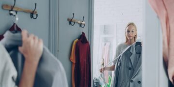 woman-sorting-clothes-wardrobe-unsplash - LONDONwebzine A woman reviewing her London wardrobe items on a bed, preparing for a seasonal transition from summer to autumn
