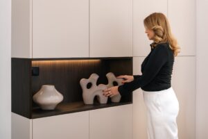 A woman arranging vases on freestanding shelves in a bright London flat, showing how to personalise a rented space.