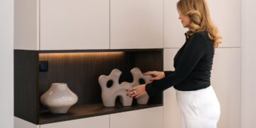 woman-styling-shelves-unsplash - LONDONwebzine A woman arranging vases on freestanding shelves in a bright London flat, showing how to personalise a rented space.