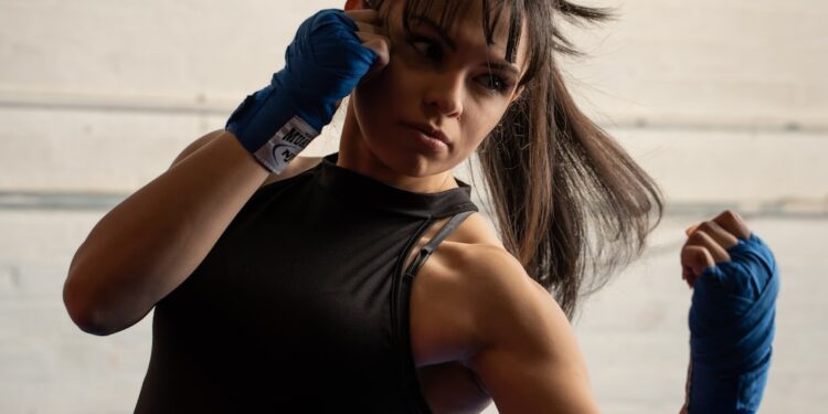 woman-wrapping-hands-boxing-gym-unsplash - LONDONwebzine A woman wrapping her hands before her first session at a boxing gym in London, preparing to train with a coach nearby