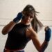 woman-wrapping-hands-boxing-gym-unsplash - LONDONwebzine A woman wrapping her hands before her first session at a boxing gym in London, preparing to train with a coach nearby