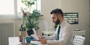 businessman-reviewing-property-documents-auction-unsplash - LONDONwebzine A focused investor reviews a legal pack before participating in commercial auctions in London