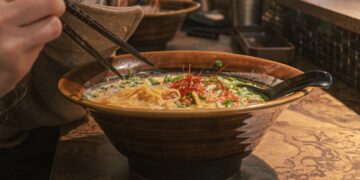 A chef ladles rich tonkotsu broth into a bowl at one of London's top ramen restaurants