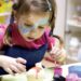A young child concentrating on a pottery wheel during kids workshops in London, guided by an art instructor in a studio.