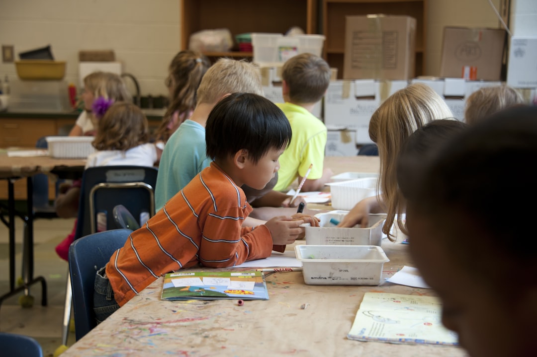 A group of children pressing ink onto paper during kids workshops, with a smiling teacher helping at a printmaking table.