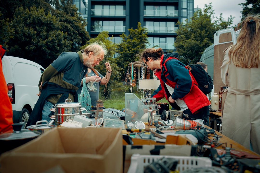 Two friends together while searching for items at vintage fairs, holding up garments against a backdrop of market stalls.