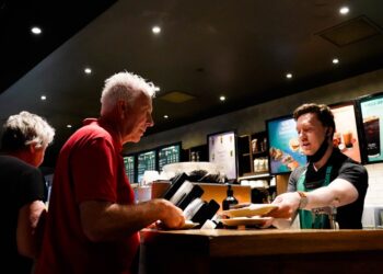 Un homme achetant des billets au comptoir de l'un des cinémas indépendants de Londres, souriant au membre du personnel