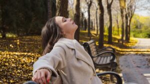 A woman walking through golden autumn leaves in a London park as part of her morning routine