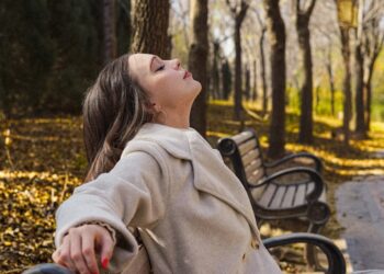 A woman walking through golden autumn leaves in a London park as part of her morning routine