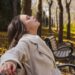 person-stretching-park-bench-autumn-unsplash - LONDONwebzine A woman walking through golden autumn leaves in a London park as part of her morning routine