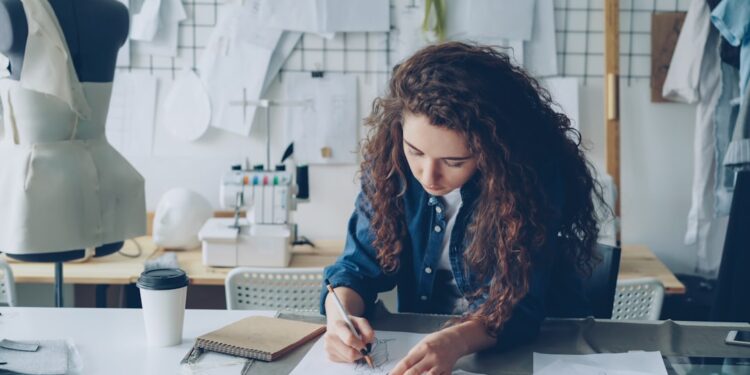 woman-designer-sustainable-fabric-studio-unsplash - LONDONwebzine A designer examines deadstock fabric in a studio, representing the sustainable fashion movement at London Fashion Week.