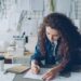 woman-designer-sustainable-fabric-studio-unsplash - LONDONwebzine A designer examines deadstock fabric in a studio, representing the sustainable fashion movement at London Fashion Week.