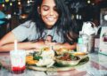 A woman sharing an Ethiopian restaurants injera platter at a table with friends in London