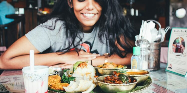 A woman sharing an Ethiopian restaurants injera platter at a table with friends in London