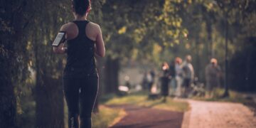woman-joining-running-club-autumn-unsplash - LONDONwebzine A smiling woman joins a running club group in a London park during autumn, wearing a light jacket and trainers.