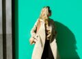 woman-layering-clothes-autumn-london-street-unsplash - LONDONwebzine A woman layering clothes on a London street in early autumn, adding a knit mid-layer over a merino base outside.