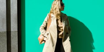 woman-layering-clothes-autumn-london-street-unsplash - LONDONwebzine A woman layering clothes on a London street in early autumn, adding a knit mid-layer over a merino base outside.