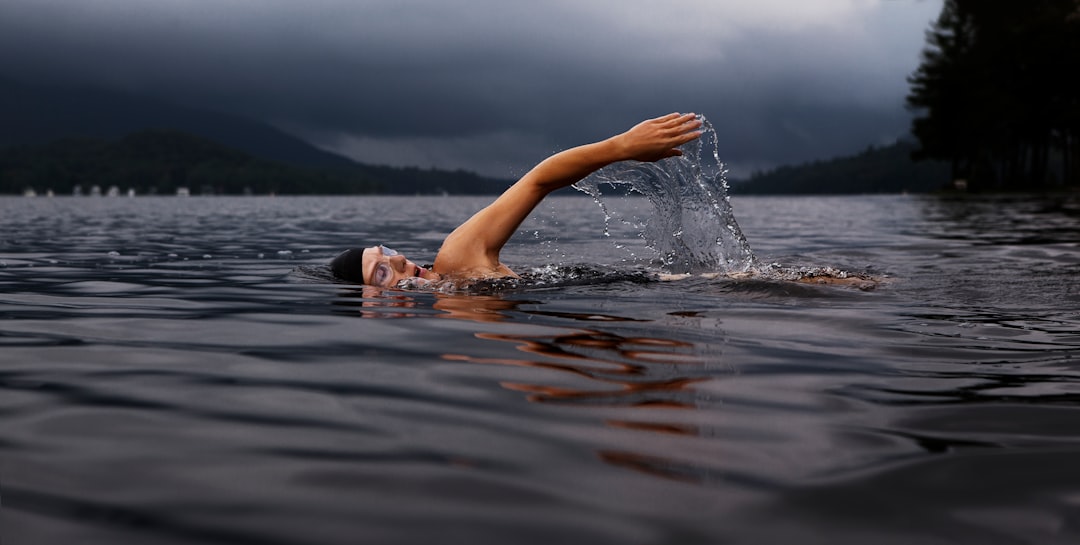 A woman enjoying wild swimming in a calm outdoor pond surrounded by greenery in London