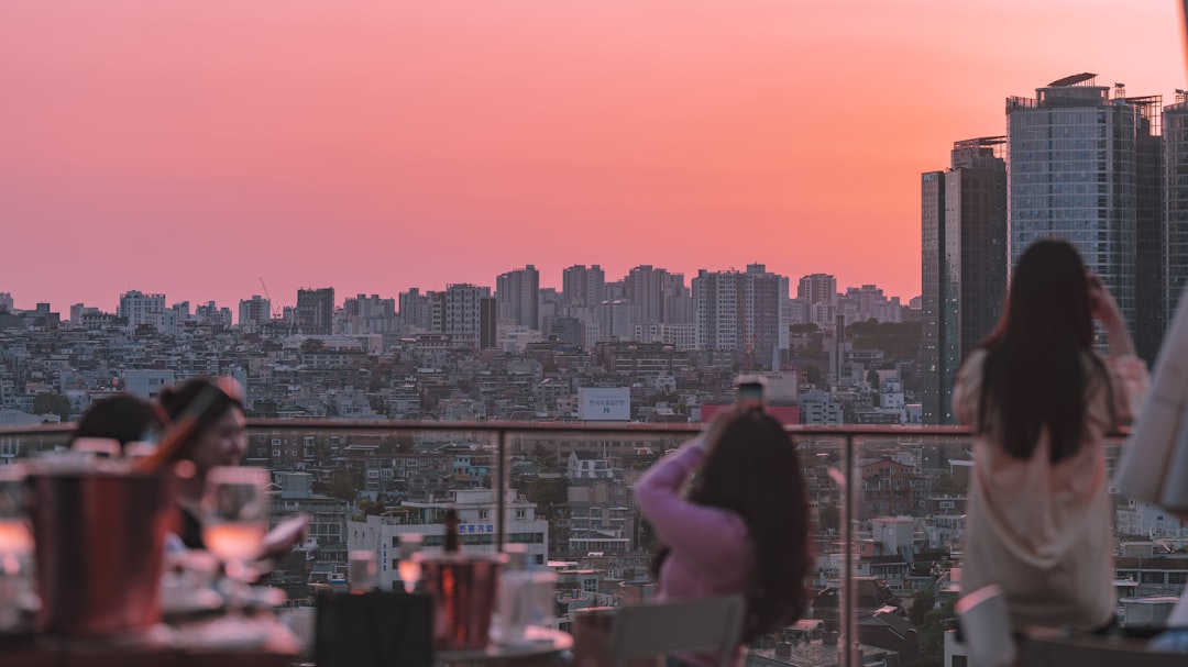 A woman enjoying cocktails at one of London's rooftop bars with the city skyline in the background on a summer evening.