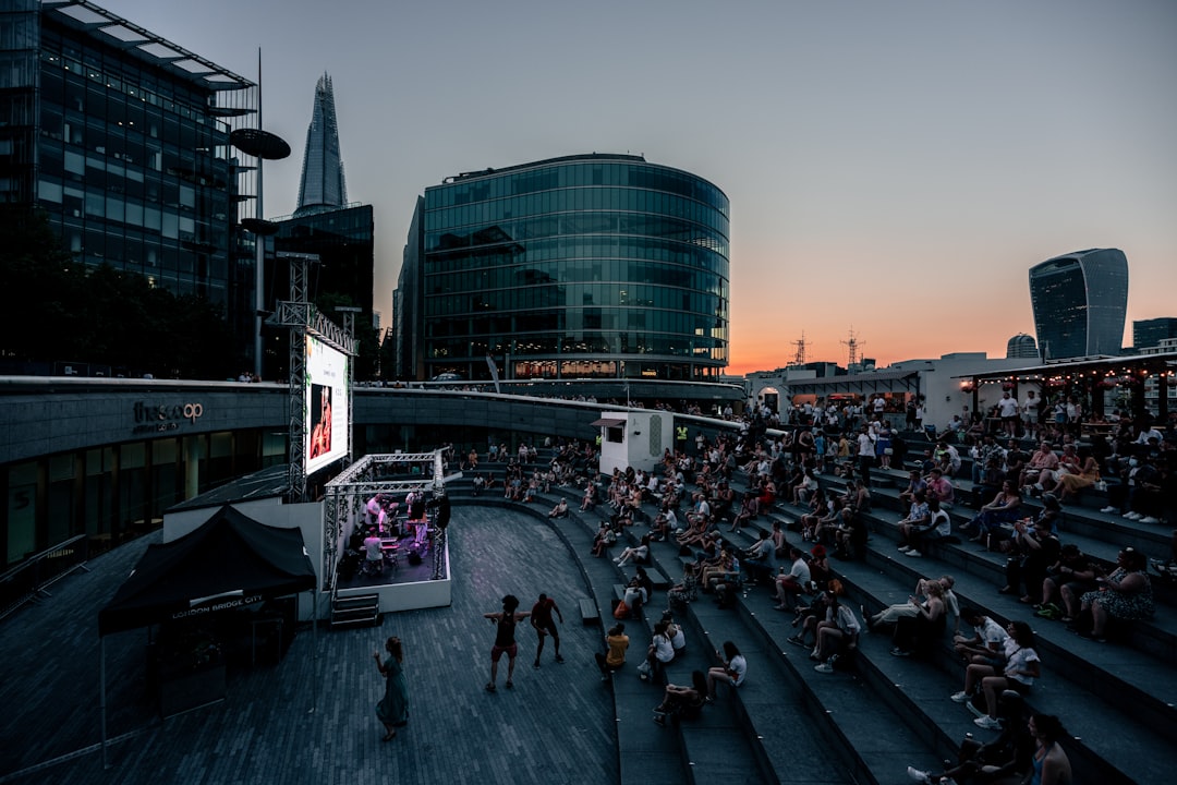 Una folla di persone che guarda uno spettacolo teatrale gratuito all'aperto in un parco di Londra durante l'estate