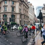 A group of beginners setting off on a road cycling club ride through a London park on a sunny morning