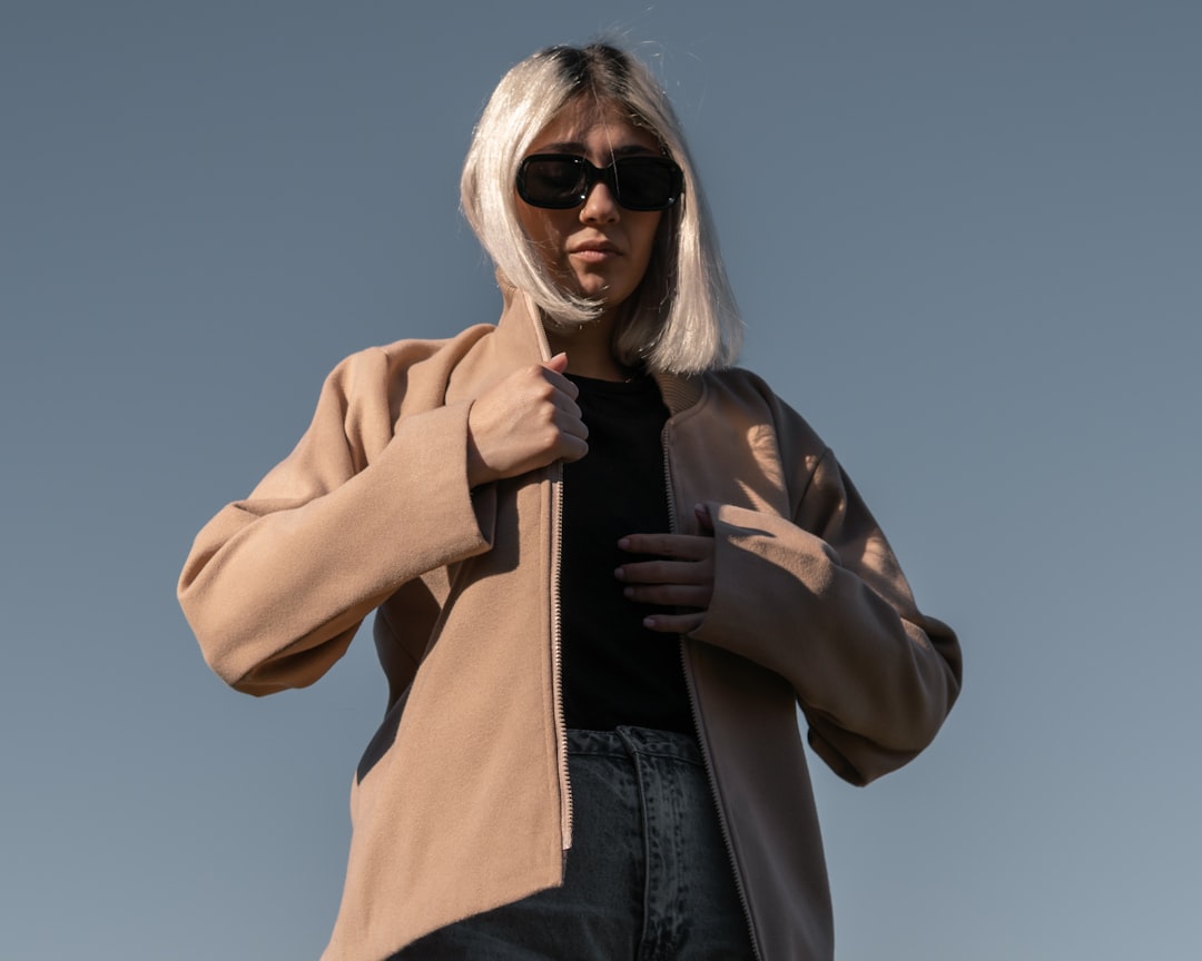 A woman in London adjusts her jacket layers, ready for a day of unpredictable August wear in the city.