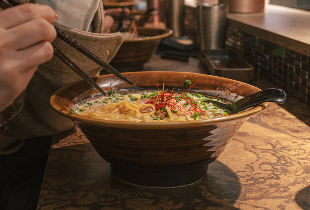 A chef ladles rich tonkotsu broth into a bowl at one of London's top ramen restaurants