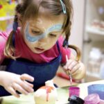A young child concentrating on a pottery wheel during kids workshops in London, guided by an art instructor in a studio.