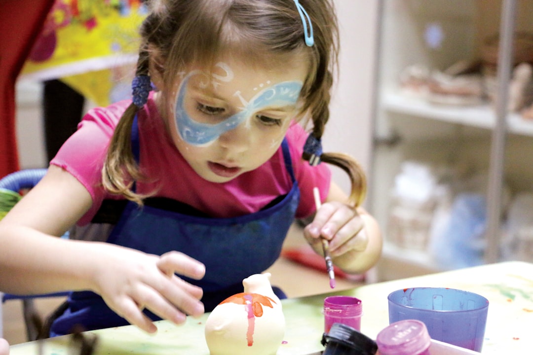 A young child concentrating on a pottery wheel during kids workshops in London, guided by an art instructor in a studio.