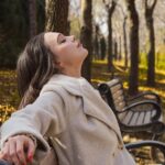 A woman walking through golden autumn leaves in a London park as part of her morning routine