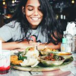 A woman sharing an Ethiopian restaurants injera platter at a table with friends in London