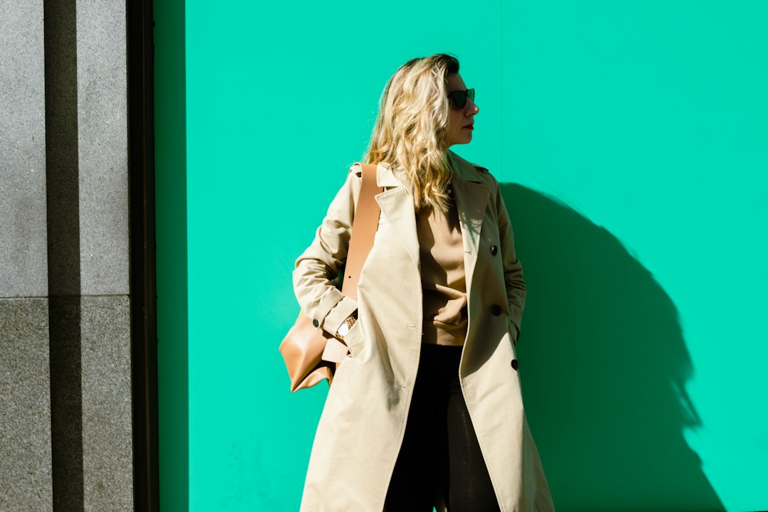 A woman layering clothes on a London street in early autumn, adding a knit mid-layer over a merino base outside.