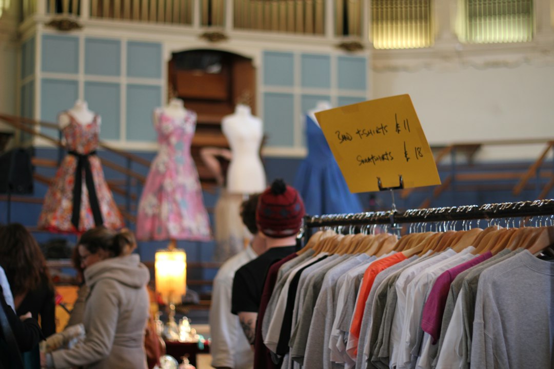 womn smiling as she browses a clothing rail at vintage fairs in London, surrounded by pre-loved coats and jackets.